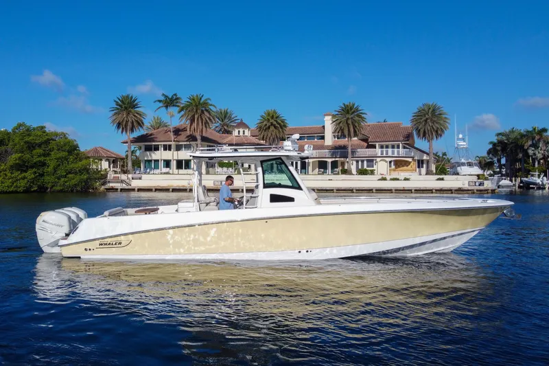  Yacht Photos Pics 2017 Boston Whaler 370 Outrage boat cruising near waterfront homes and palm trees.