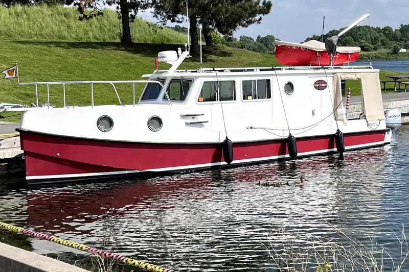 Lenore Yacht Photos Pics 2023 Great Harbour Trawlers TT35 boat docked on a calm lake with lush greenery.