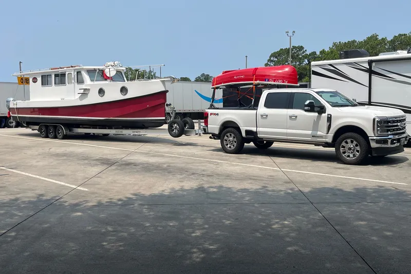 Lenore Yacht Photos Pics 2023 Great Harbour Trawlers TT35 on trailer, towed by white pickup truck in parking lot.