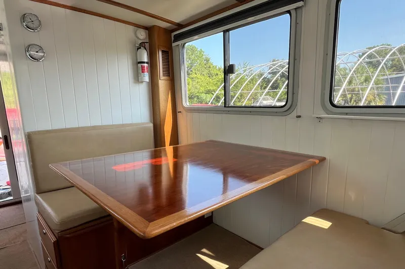 Lenore Yacht Photos Pics Interior of 2023 Great Harbour Trawlers TT35 with wooden table and cushioned seating.