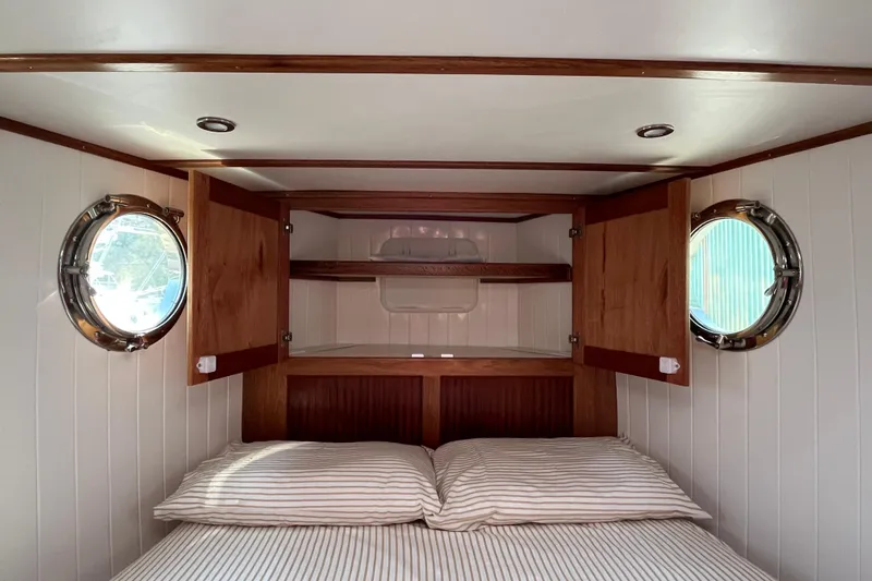 Lenore Yacht Photos Pics Cozy cabin interior of 2023 Great Harbour TT35 with wooden shelves and porthole windows.