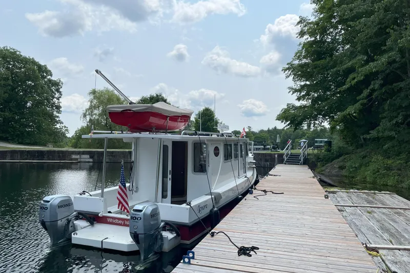 Lenore Yacht Photos Pics 2023 Great Harbour TT35 boat docked by a wooden pier, surrounded by trees.