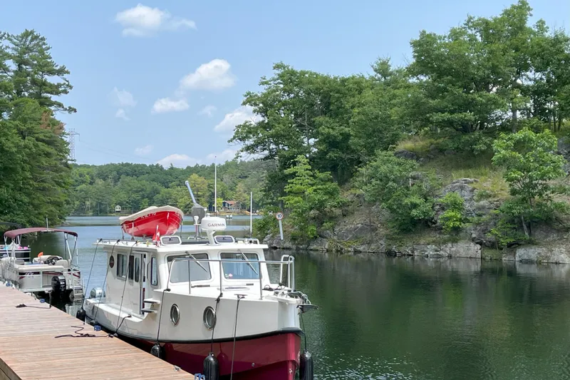 Lenore Yacht Photos Pics Great Harbour TT35 boat docked by a scenic, tree-lined riverbank, 2023 model.