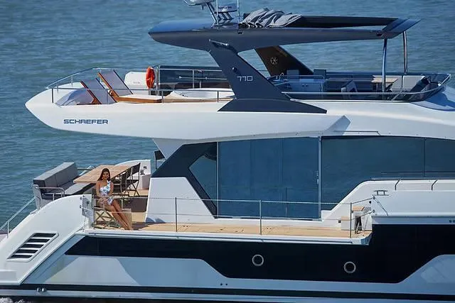 Luxury Schaefer 770 yacht cruising on water, 2026 model, with a person relaxing on deck.