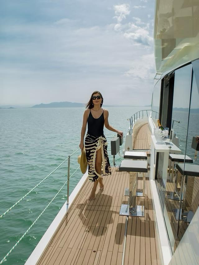 Woman walking on Schaefer 770 yacht deck, 2026 model, ocean view.
