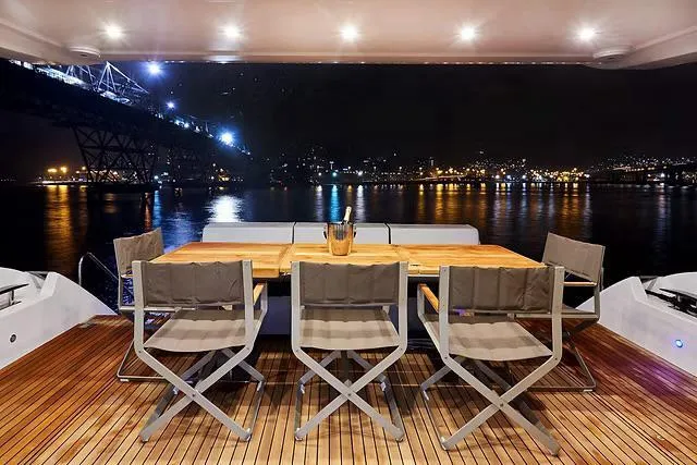 Yacht Photos Pics Luxurious Schaefer 770 yacht deck with dining area, overlooking illuminated cityscape at night, 2026 model.