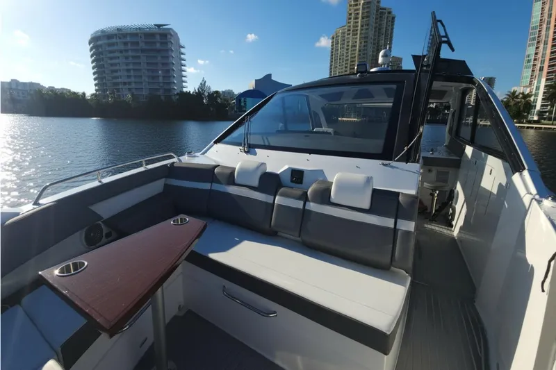  Yacht Photos Pics 2021 Cruisers Yachts 42 GLS OB interior with seating and table, docked by waterfront buildings.