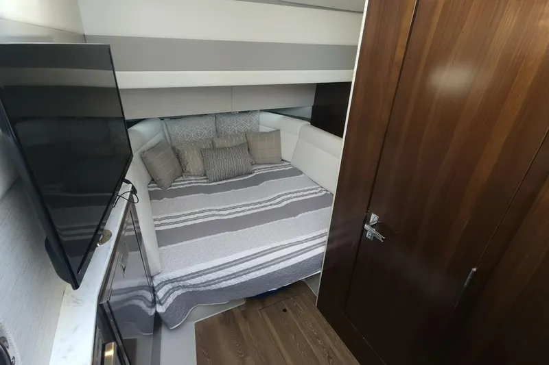  Yacht Photos Pics 2021 Cruisers Yachts 42 GLS OB cabin interior with bed, TV, and wooden door.