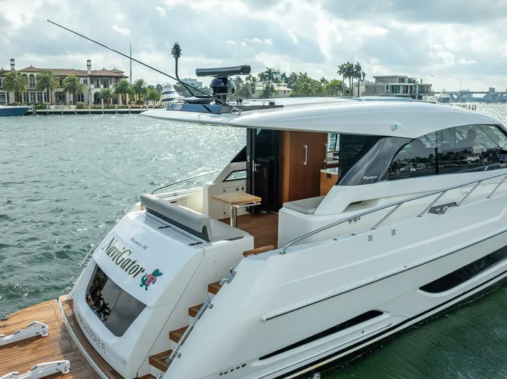Man Cave Yacht Photos Pics 2021 Maritimo X50 yacht docked by waterfront homes, showcasing sleek design and luxury features.
