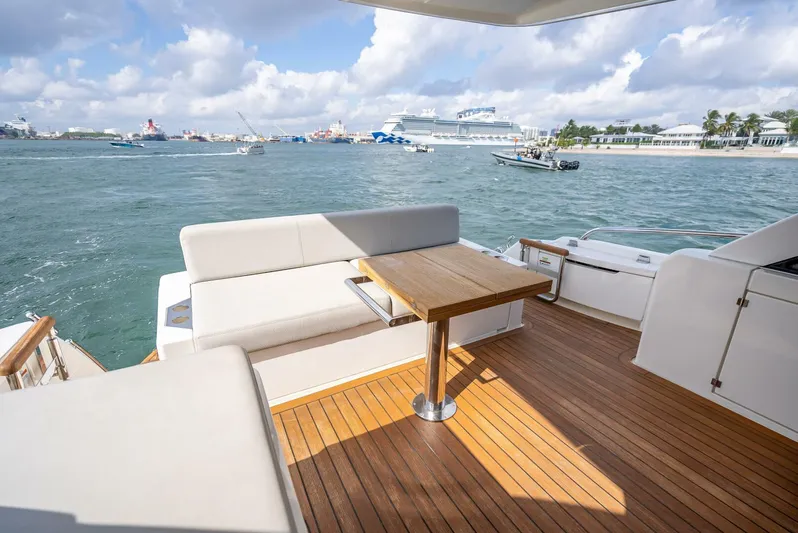 Man Cave Yacht Photos Pics 2021 Maritimo X50 yacht deck with seating and table, overlooking a scenic harbor.