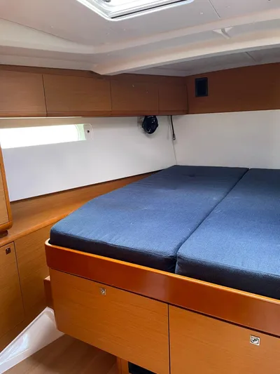 Hygge Yacht Photos Pics Interior cabin of 2017 Jeanneau Sun Odyssey 479 with wooden finish and blue bedding.