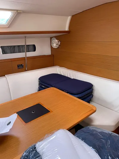 Hygge Yacht Photos Pics Interior of 2017 Jeanneau Sun Odyssey 479 sailboat with wooden table and white seating.