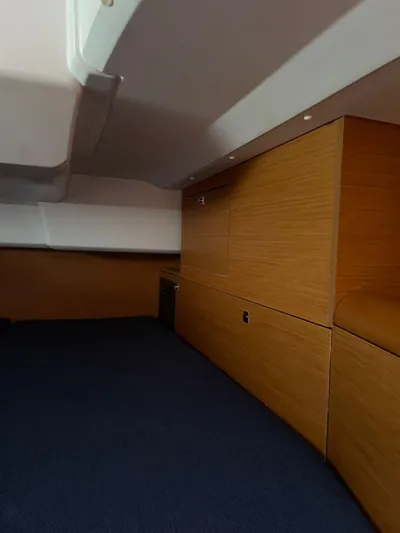 Hygge Yacht Photos Pics Interior cabin of 2017 Jeanneau Sun Odyssey 479 yacht, featuring wood paneling and blue carpet.