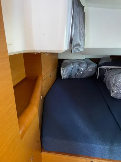 Hygge Yacht Photos Pics Cozy cabin interior of 2017 Jeanneau Sun Odyssey 479 with blue bedding and wooden storage.
