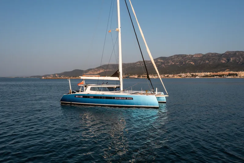 Ondine Blue Yacht Photos Pics Blue Balance 526 catamaran sailing on calm sea with mountainous coastline in background, 2016 model.