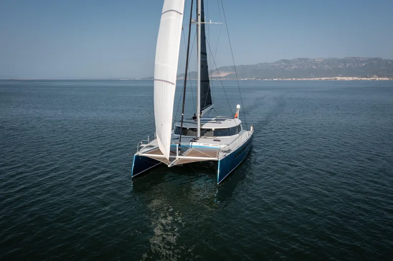Ondine Blue Yacht Photos Pics Sailing catamaran Balance 526, 2016 model, cruising on calm waters with distant mountains.