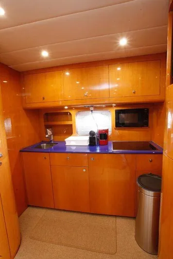 Yacht Photos Pics Luxurious wooden yacht kitchen with blue countertop, sink, microwave, and modern lighting. Uniesse 57, 2000 model.