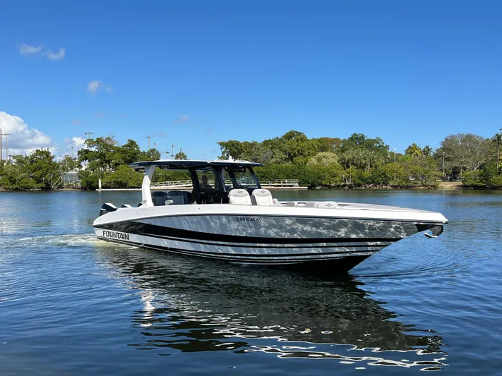  Yacht Photos Pics 2023 Fountain 38 SCX boat cruising on a calm lake under a clear blue sky.