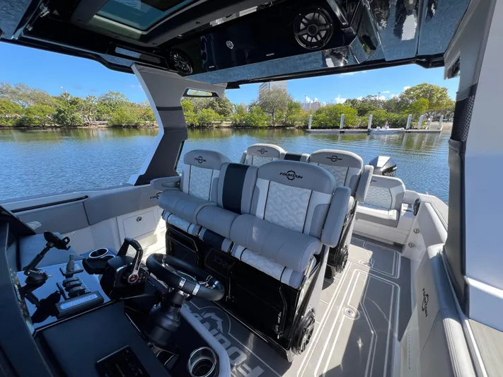  Yacht Photos Pics 2023 Fountain 38 SCX boat interior with modern seating and controls on a calm waterway.