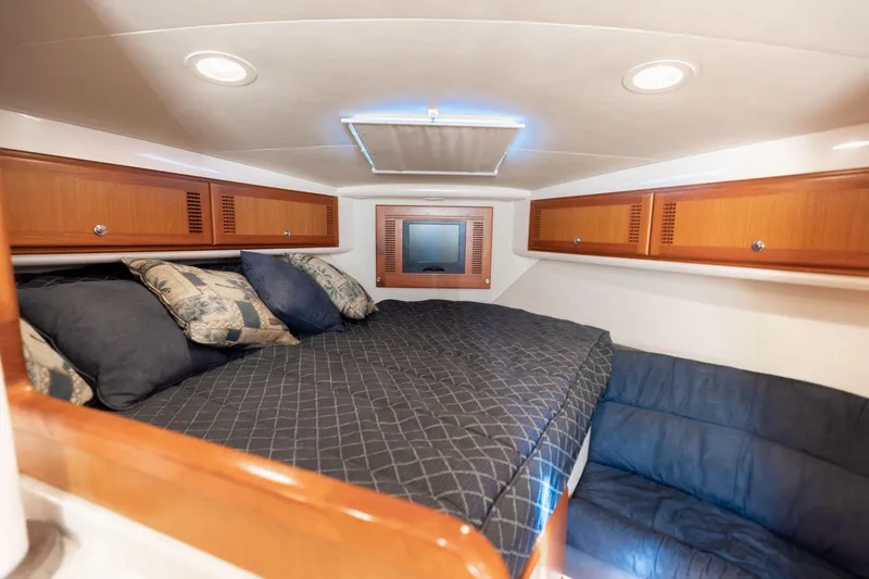 Miss Big Gun Yacht Photos Pics Luxurious cabin interior of 2000 Cabo 35 Express yacht with cozy bedding and wooden cabinets.