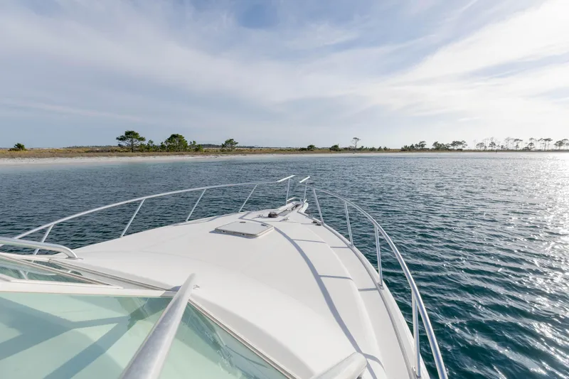 Miss Big Gun Yacht Photos Pics Bow view of 2000 Cabo 35 Express yacht approaching a scenic shoreline.