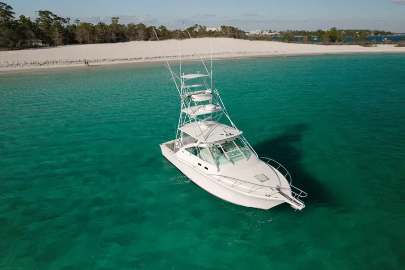 Miss Big Gun Yacht Photos Pics 2000 Cabo 35 Express boat on turquoise water near sandy beach.