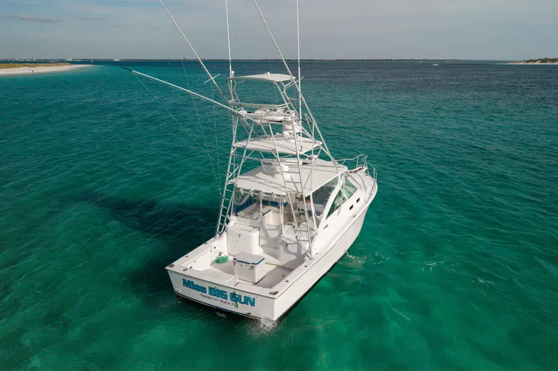 Miss Big Gun Yacht Photos Pics 2000 Cabo 35 Express boat on clear turquoise water, rear view.