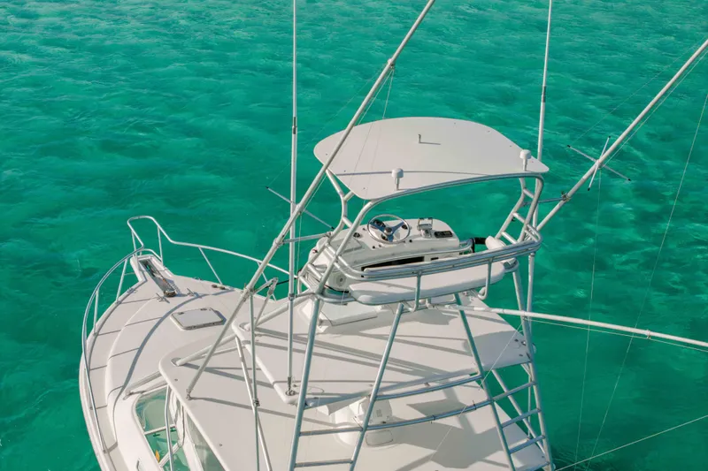 Miss Big Gun Yacht Photos Pics 2000 Cabo 35 Express boat on clear turquoise water, showcasing upper deck and controls.