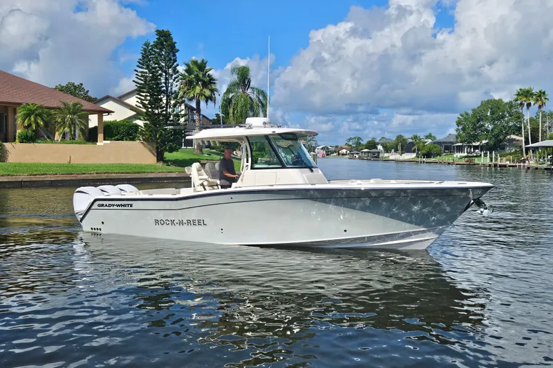  Yacht Photos Pics 2022 Grady-White Canyon 336 boat cruising on a scenic waterway under a blue sky.