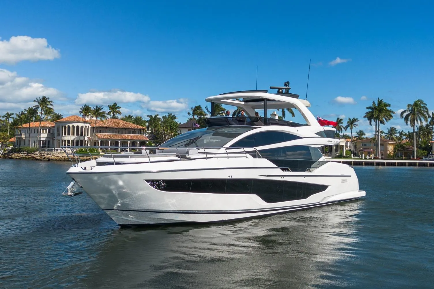 Luxurious 2025 Pearl 72 yacht cruising near waterfront mansions and palm trees.