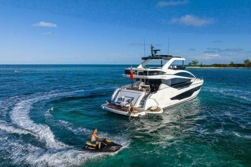 Pearl 72 Indulgence Yacht Photos Pics Luxurious 2025 Pearl 72 yacht on clear blue ocean with jet ski nearby.