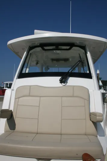  Yacht Photos Pics 2018 Pursuit S 328 Sport boat with beige seating and windshield, docked under clear blue sky.