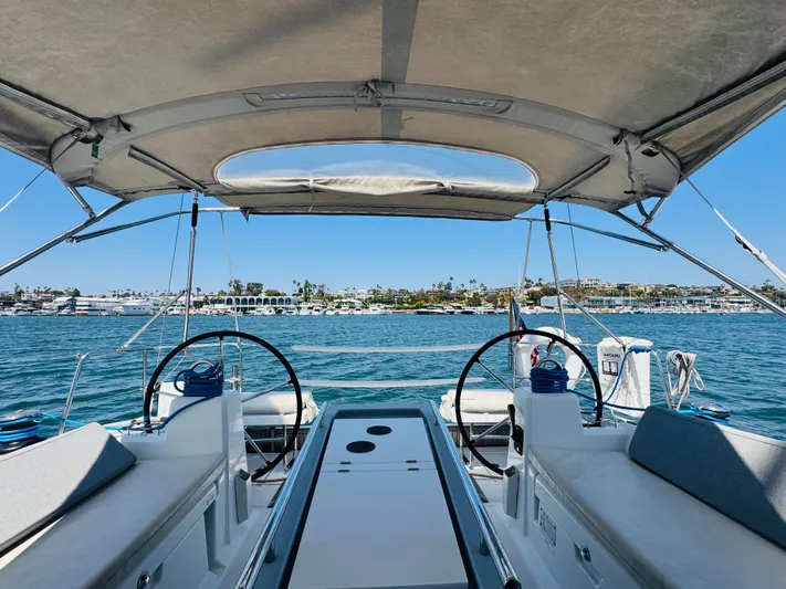 Happy Hour Yacht Photos Pics Beneteau Oceanis 41.1 sailboat cockpit view, 2020 model, overlooking serene waters and distant shoreline.