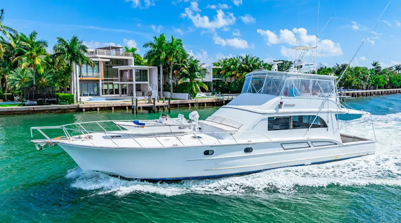 Bahama Belle Yacht Photos Pics White 1996 Blackwell 72 yacht cruising near modern waterfront homes.