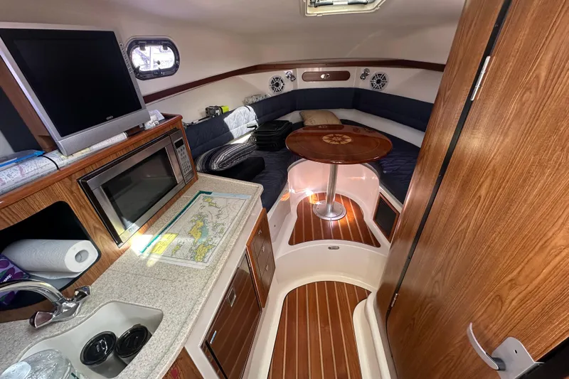  Yacht Photos Pics 2010 Pursuit OS 315 Offshore cabin interior with kitchenette, seating, and wooden accents.
