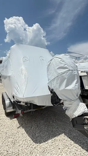  Yacht Photos Pics 2026 Ranger Tugs R-27 boat covered in protective wrap on a trailer, under a cloudy sky.