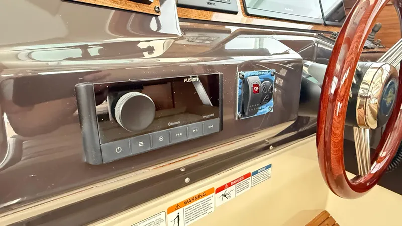  Yacht Photos Pics 2026 Ranger Tugs R-27 dashboard with Fusion audio system and wooden steering wheel.