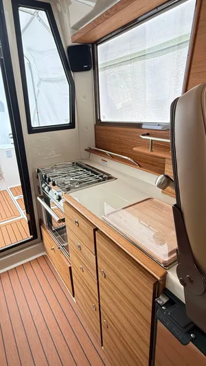  Yacht Photos Pics 2026 Ranger Tugs R-27 interior kitchen with stove, wooden cabinetry, and modern design.