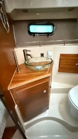  Yacht Photos Pics 2026 Ranger Tugs R-27 bathroom with glass sink, wooden cabinetry, and small window.