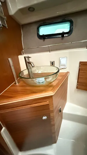  Yacht Photos Pics 2026 Ranger Tugs R-27 bathroom with glass sink and wooden cabinetry.