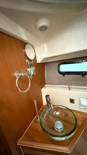  Yacht Photos Pics 2026 Ranger Tugs R-27 bathroom with glass sink, wooden countertop, and porthole window.