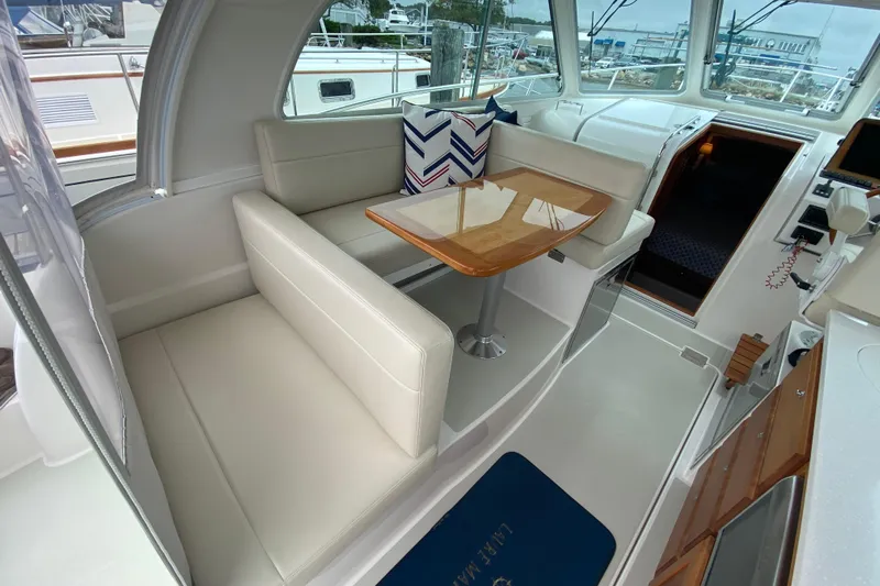Laure Marie Yacht Photos Pics 2020 Back Cove 34O interior with white seating, wooden table, and nautical decor.