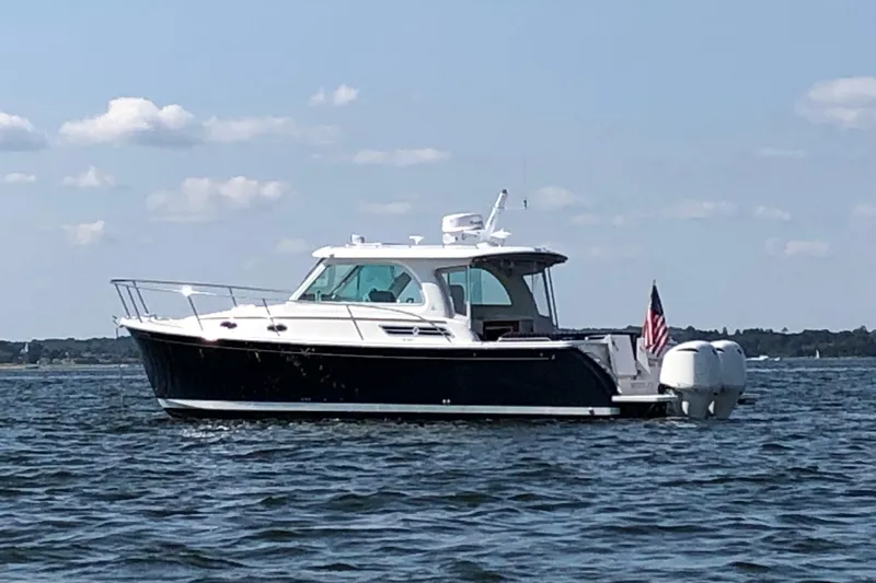 Laure Marie Yacht Photos Pics 2020 Back Cove 34O boat on calm water, clear sky, American flag displayed.