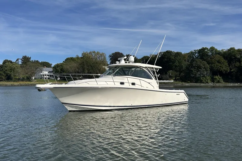  Yacht Photos Pics 2014 Pursuit OS 385 Offshore boat on calm water, surrounded by trees and houses.