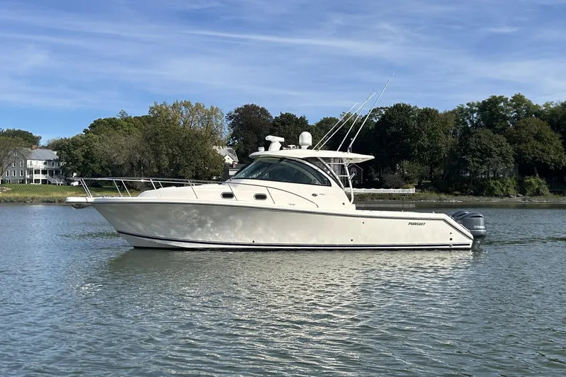  Yacht Photos Pics 2014 Pursuit OS 385 Offshore boat on calm water, surrounded by trees and houses.