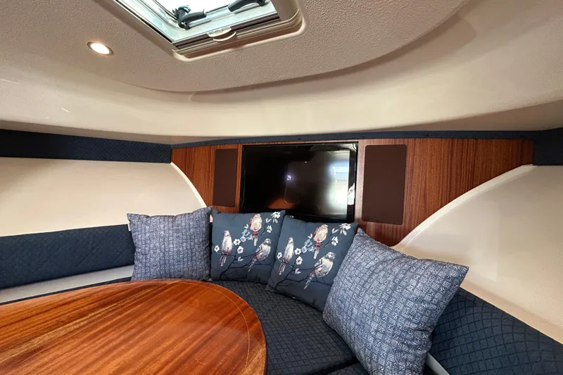  Yacht Photos Pics 2014 Pursuit OS 385 Offshore cabin interior with cushions and wooden table.