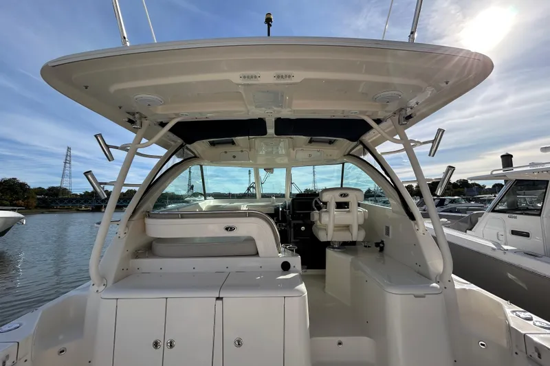  Yacht Photos Pics 2014 Pursuit OS 385 Offshore boat interior with seating and helm, docked by the water.