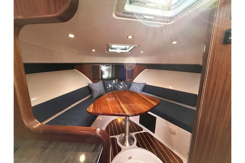  Yacht Photos Pics 2014 Pursuit OS 385 Offshore cabin interior with wooden table and seating.