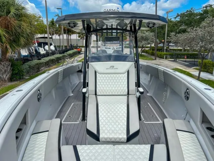  Yacht Photos Pics 2023 AMP Arth 333 boat interior with white cushioned seating and Garmin navigation system.