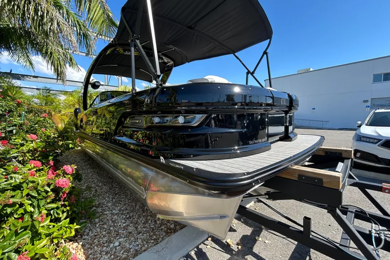 Yacht Photos Pics 2026 Avalon Excalibur 27-foot pontoon boat on trailer, surrounded by tropical plants.